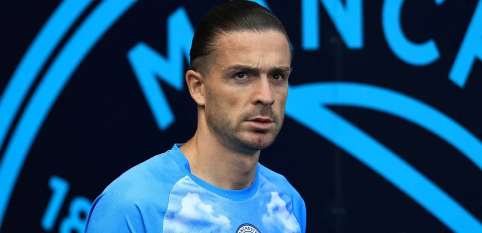 Player in blue kit standing before Manchester City backdrop