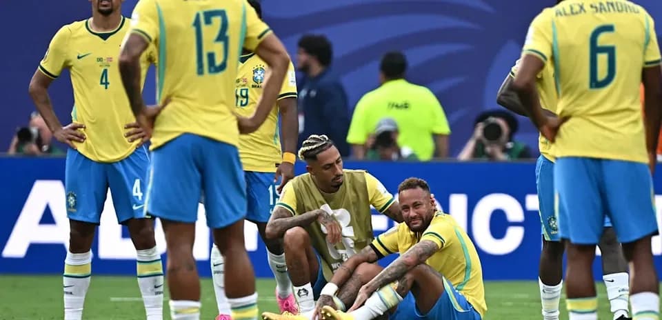 Neymar sitting on the field with teammates nearby