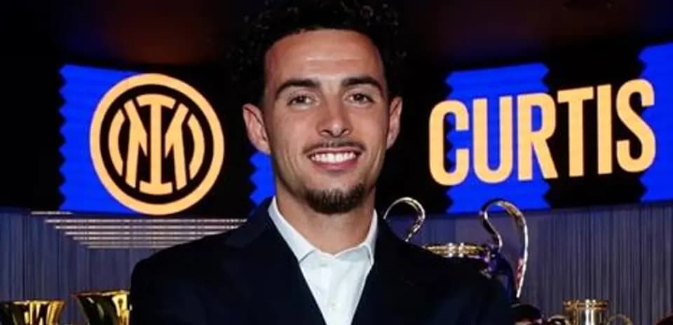 Player smiling at press event with trophies behind