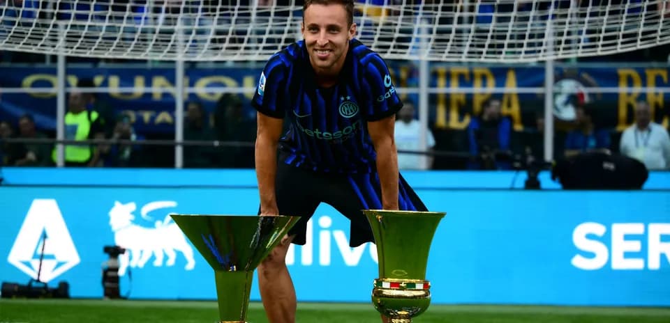 Player celebrating with two trophies on the field