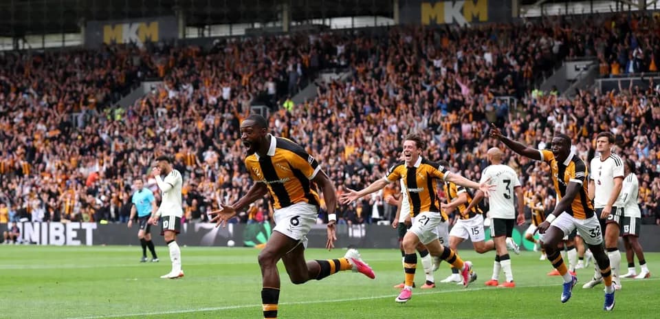 Players celebrating a goal in front of fans