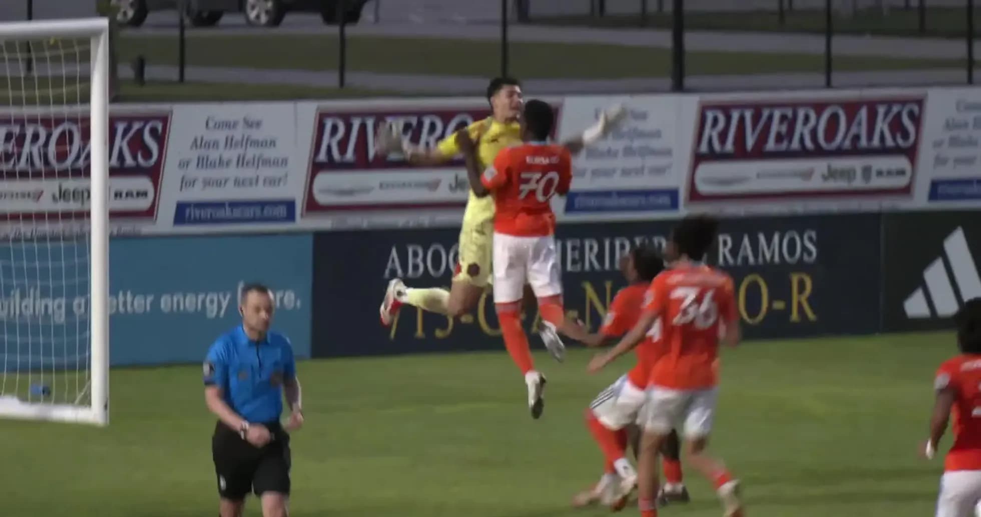 Goalkeeper jumps to catch the ball during match