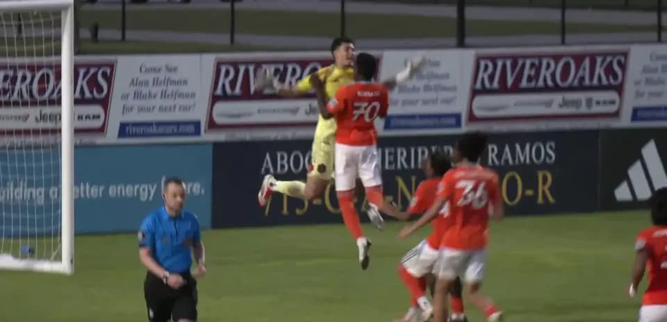 Goalkeeper jumps to catch the ball during match