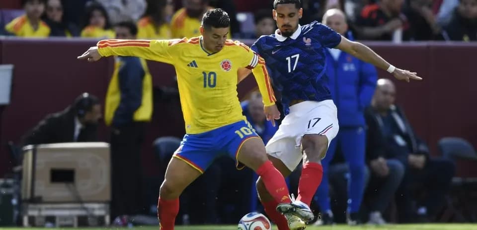 Colombian player competing for the ball against French player