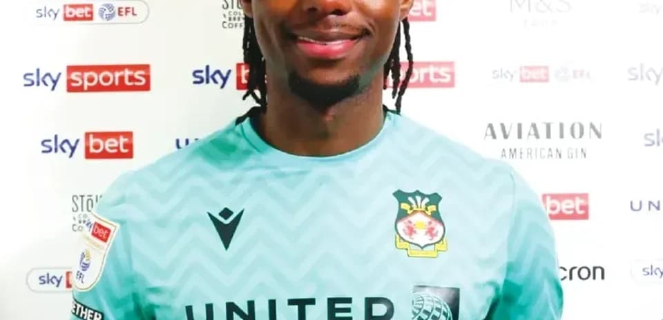 Player in green goalkeeper kit at press backdrop