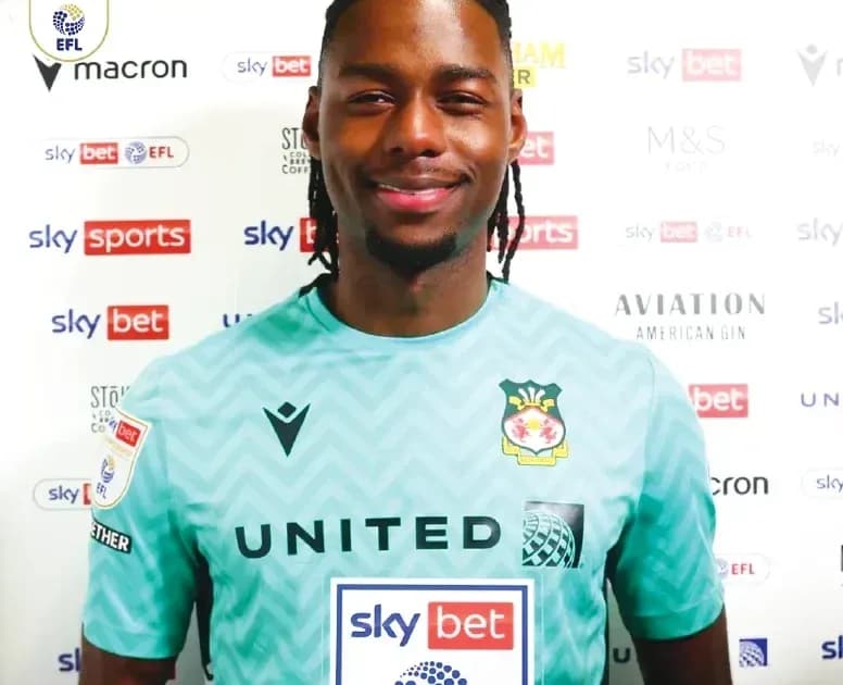 Player in green goalkeeper kit at press backdrop