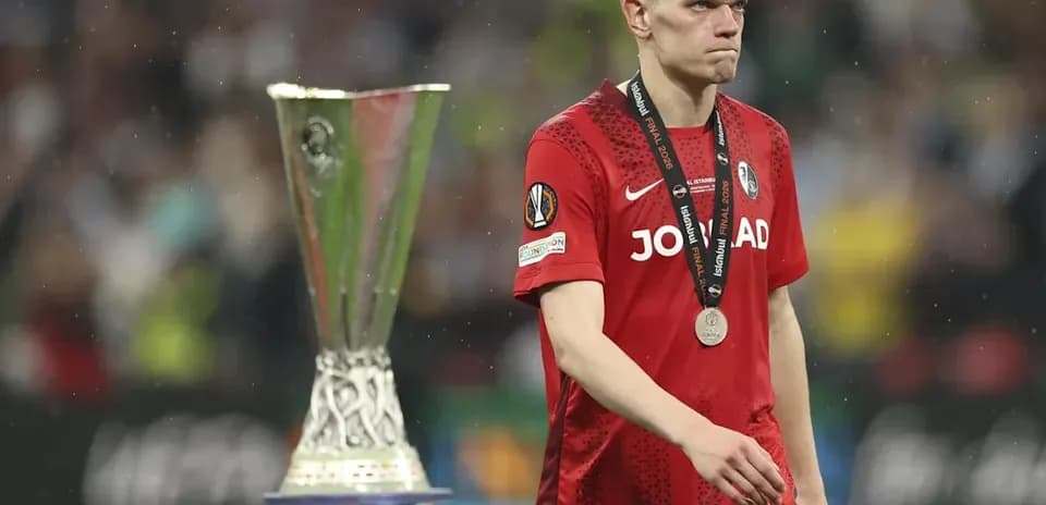 Player in red jersey walking past trophy after match