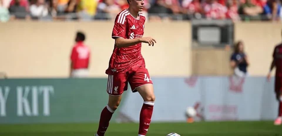 Player in red Liverpool kit dribbling ball on field