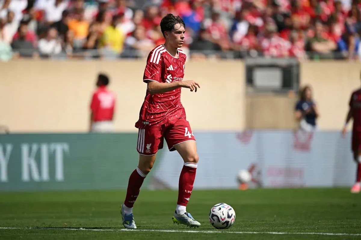 Player in red Liverpool kit dribbling ball on field