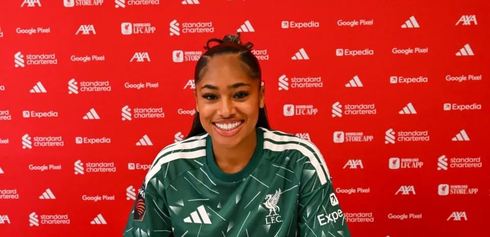 Player smiling at press conference with Liverpool backdrop