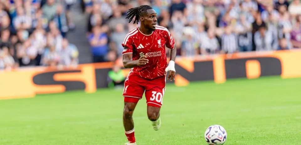 Player in red kit running with soccer ball on pitch