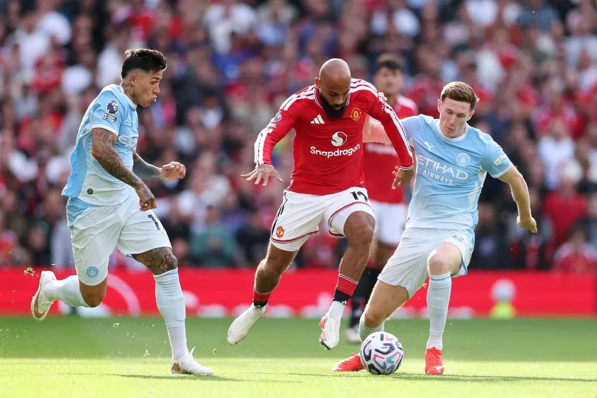 Manchester United player challenged by Manchester City defenders
