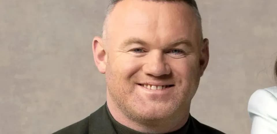 Man smiling in a black jacket with a neutral background