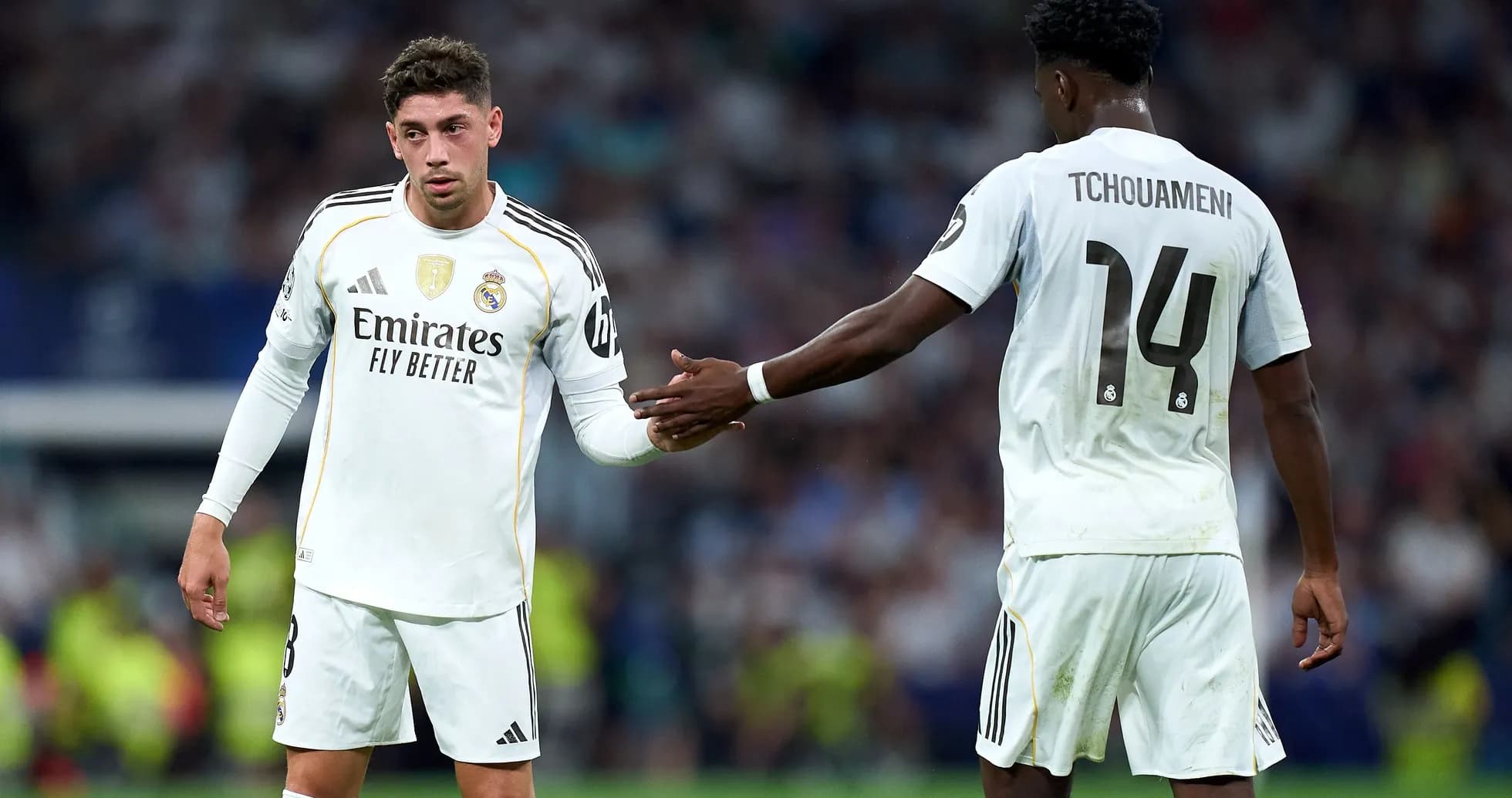 Two Real Madrid players exchanging a handshake on field