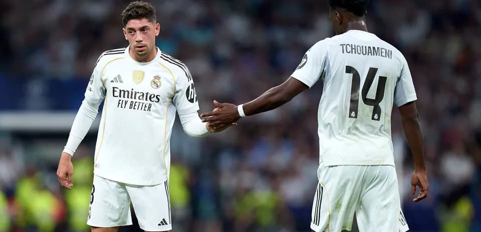 Two Real Madrid players exchanging a handshake on field