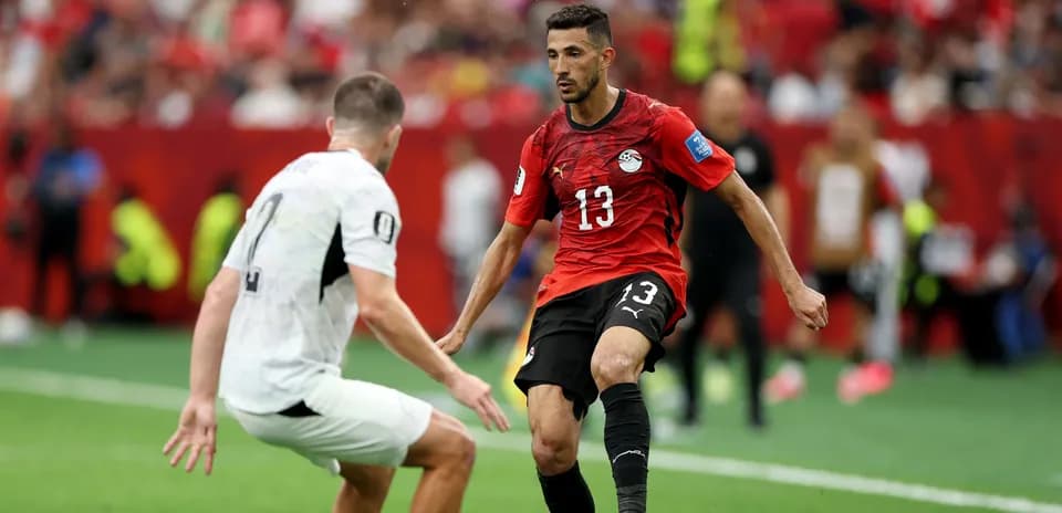 Player in red jersey dribbling past opponent on field