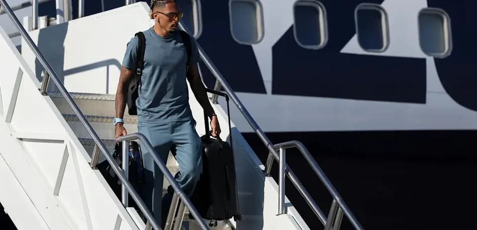 Player descending airplane stairs with luggage