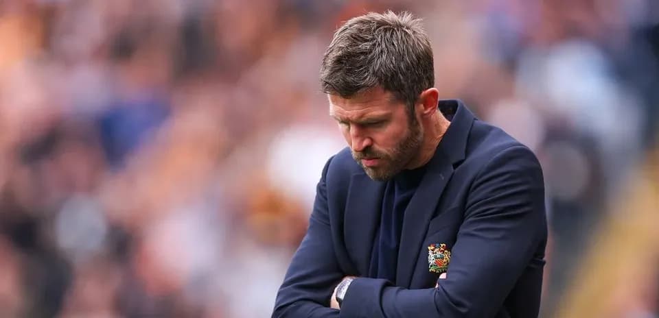 Manager with arms crossed looking down on sideline