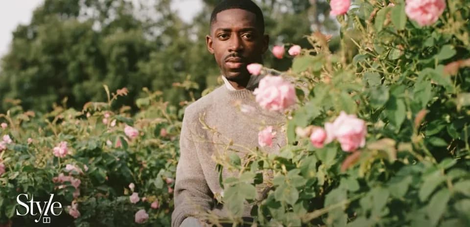 Man sitting among pink roses in garden