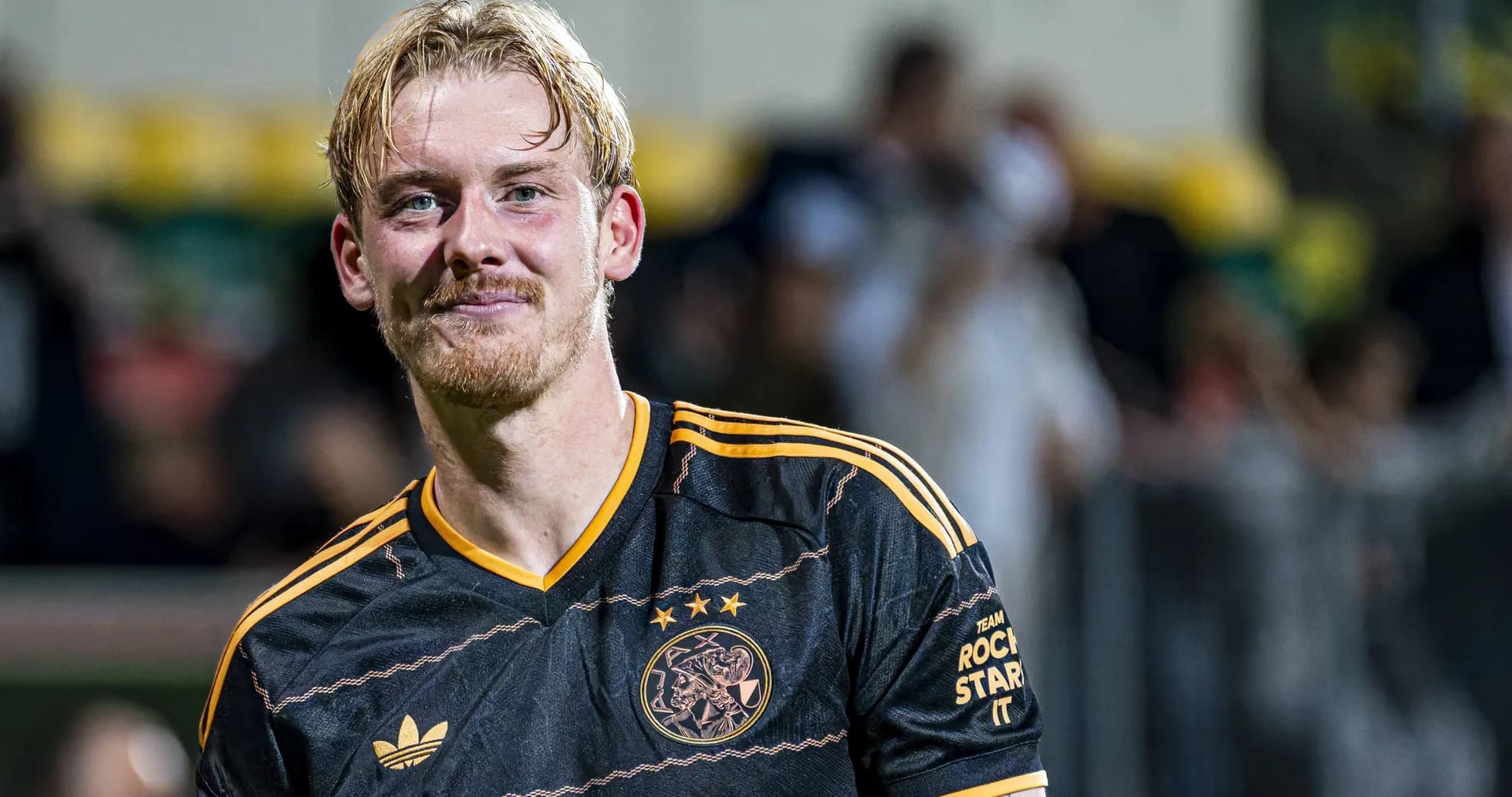 Player smiling in Ajax black and orange jersey