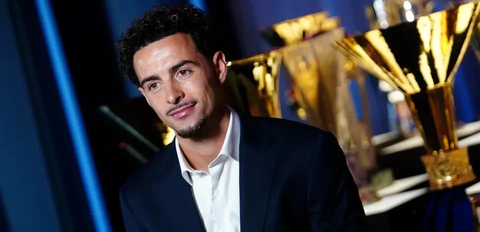 Player posing in front of multiple trophies