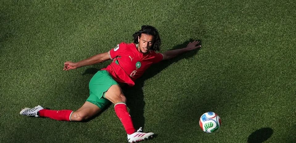 Player sliding on grass with soccer ball nearby