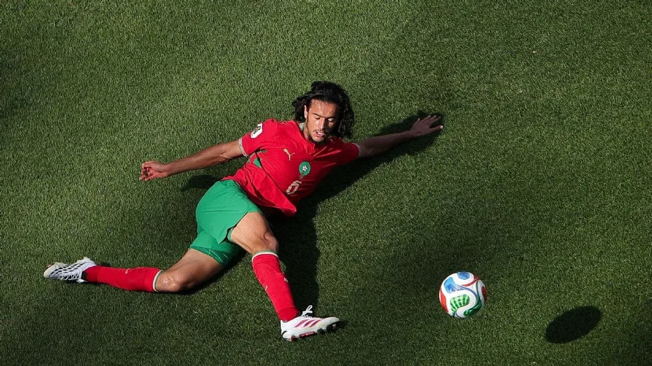 Player sliding on grass with soccer ball nearby