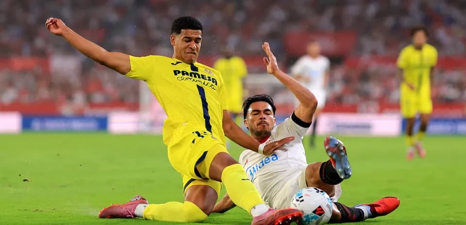 Villarreal player tackling Sevilla opponent on field