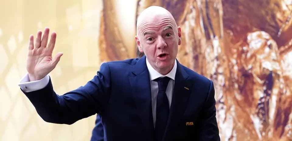 FIFA official waving during event with trophy backdrop