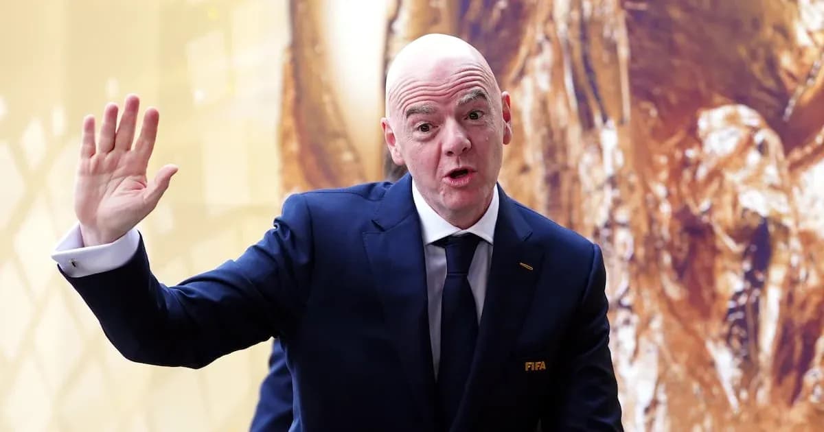 FIFA official waving during event with trophy backdrop