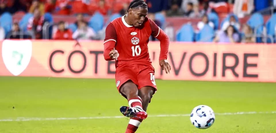 Player in red jersey striking soccer ball on field