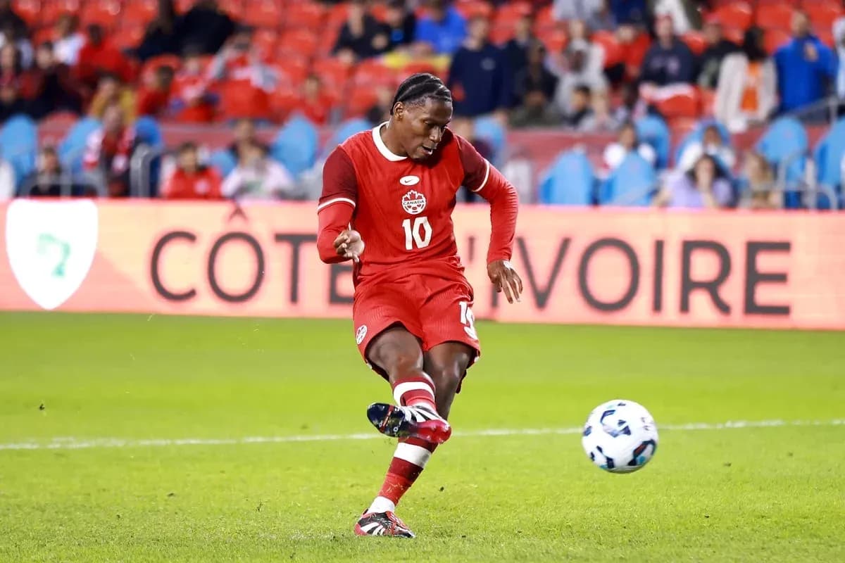 Player in red jersey striking soccer ball on field