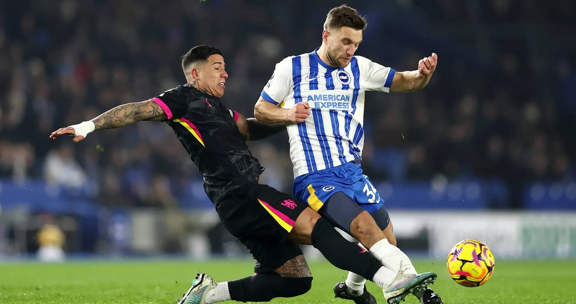 Brighton player challenging Chelsea opponent for the ball