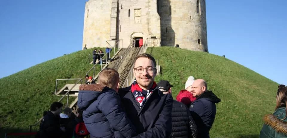 Man holding child in front of historic tower