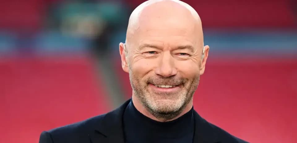 Man smiling in a suit at stadium