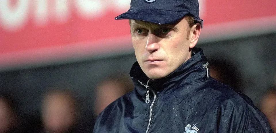 Coach wearing a cap during a rainy match