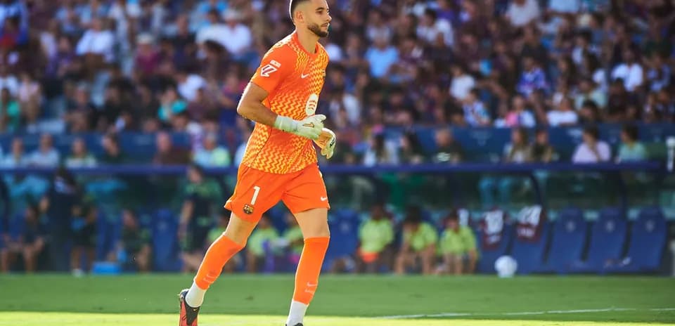 Goalkeeper in orange kit running on the pitch