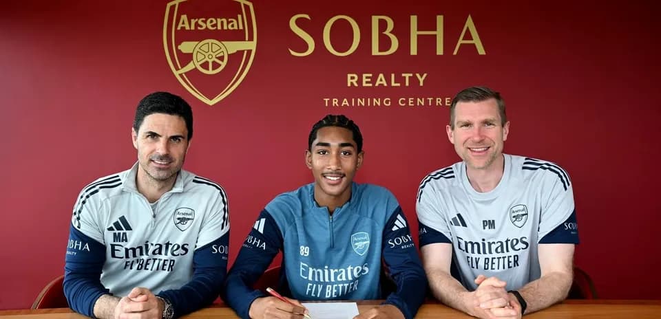 Player signing contract with Arsenal staff at training center
