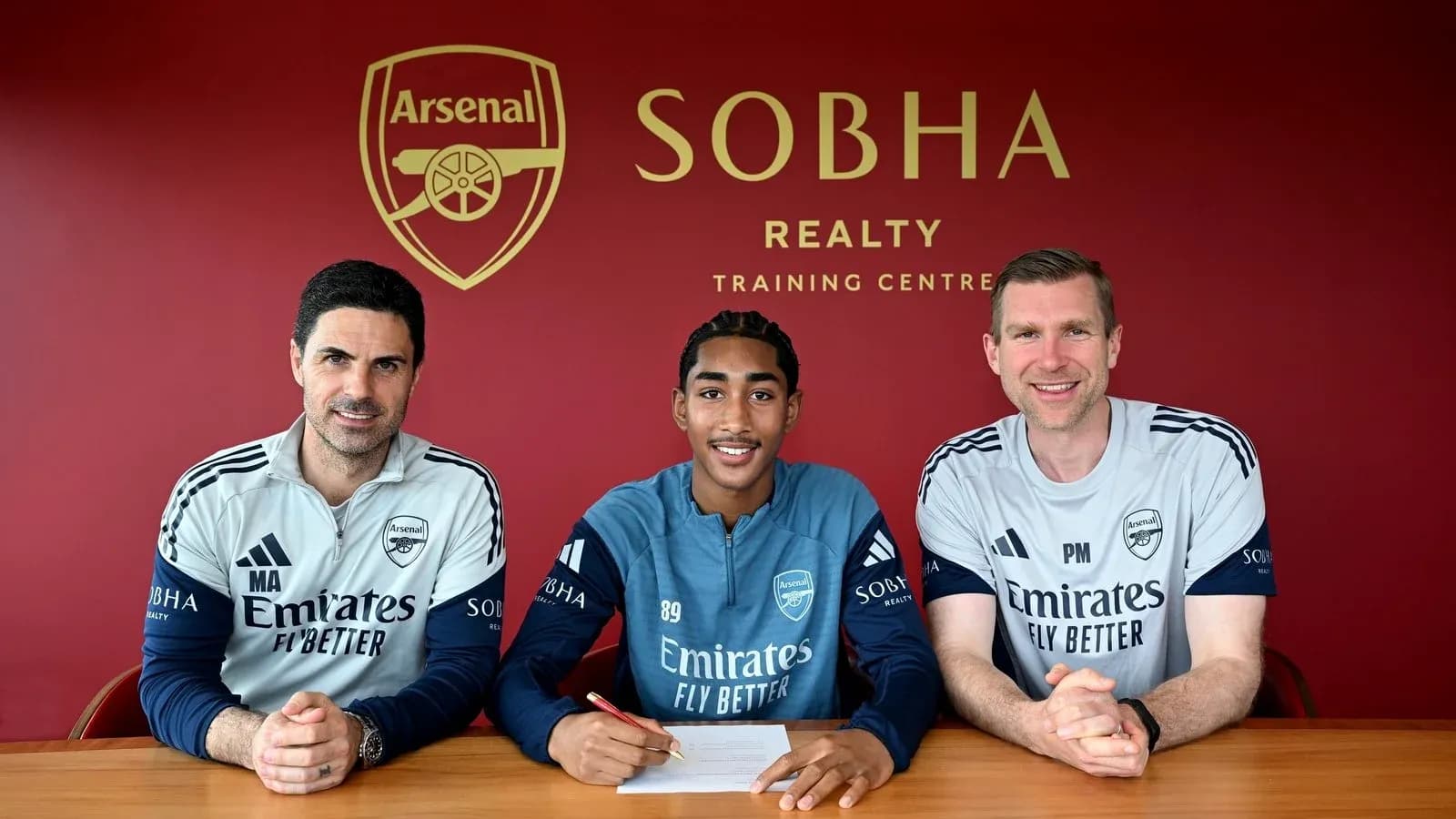 Player signing contract with Arsenal staff at training center