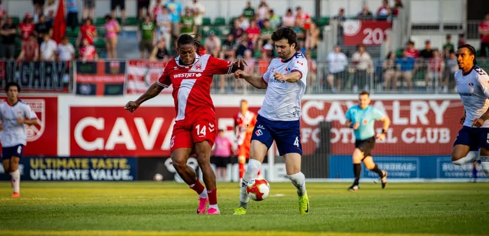 Cavalry FC player challenging Supra du Quebec opponent