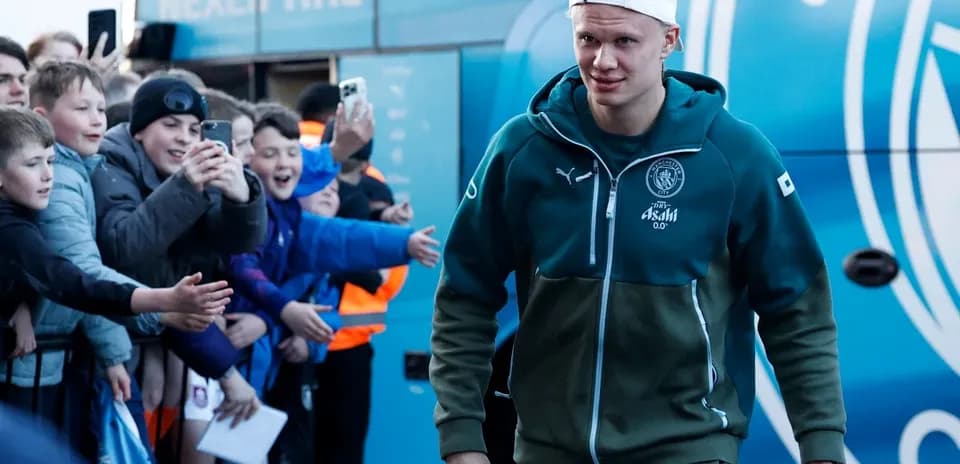 Player arriving at team bus with fans cheering