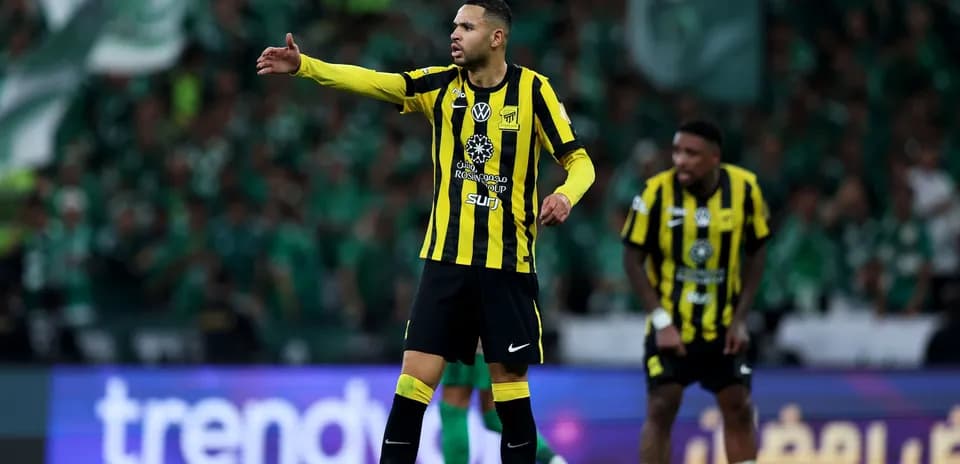 Player gesturing during match with green crowd behind
