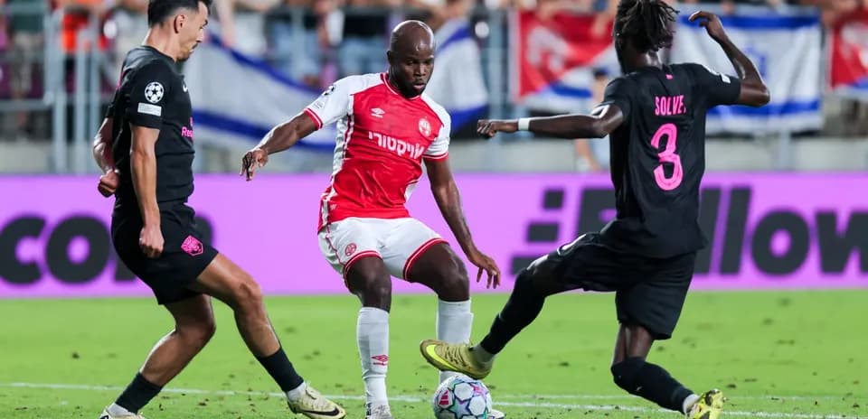 Sabah FA player dribbling past Hapoel defenders