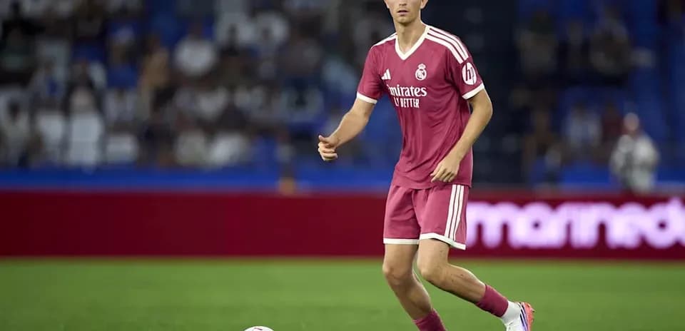 Player in pink kit dribbling ball on field