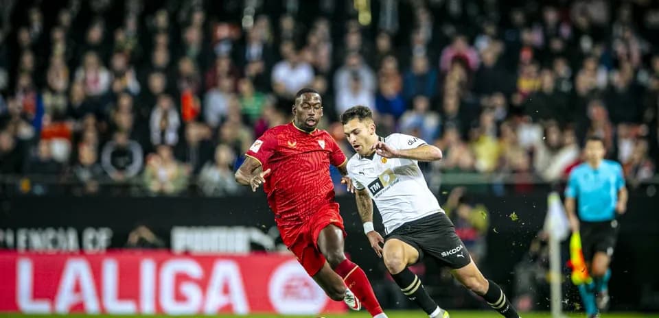 Sevilla player challenging Valencia player for the ball