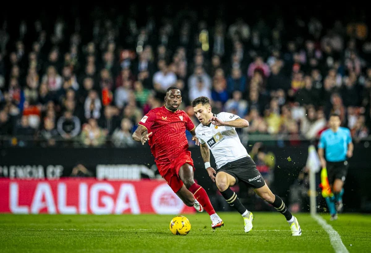 Sevilla player challenging Valencia player for the ball