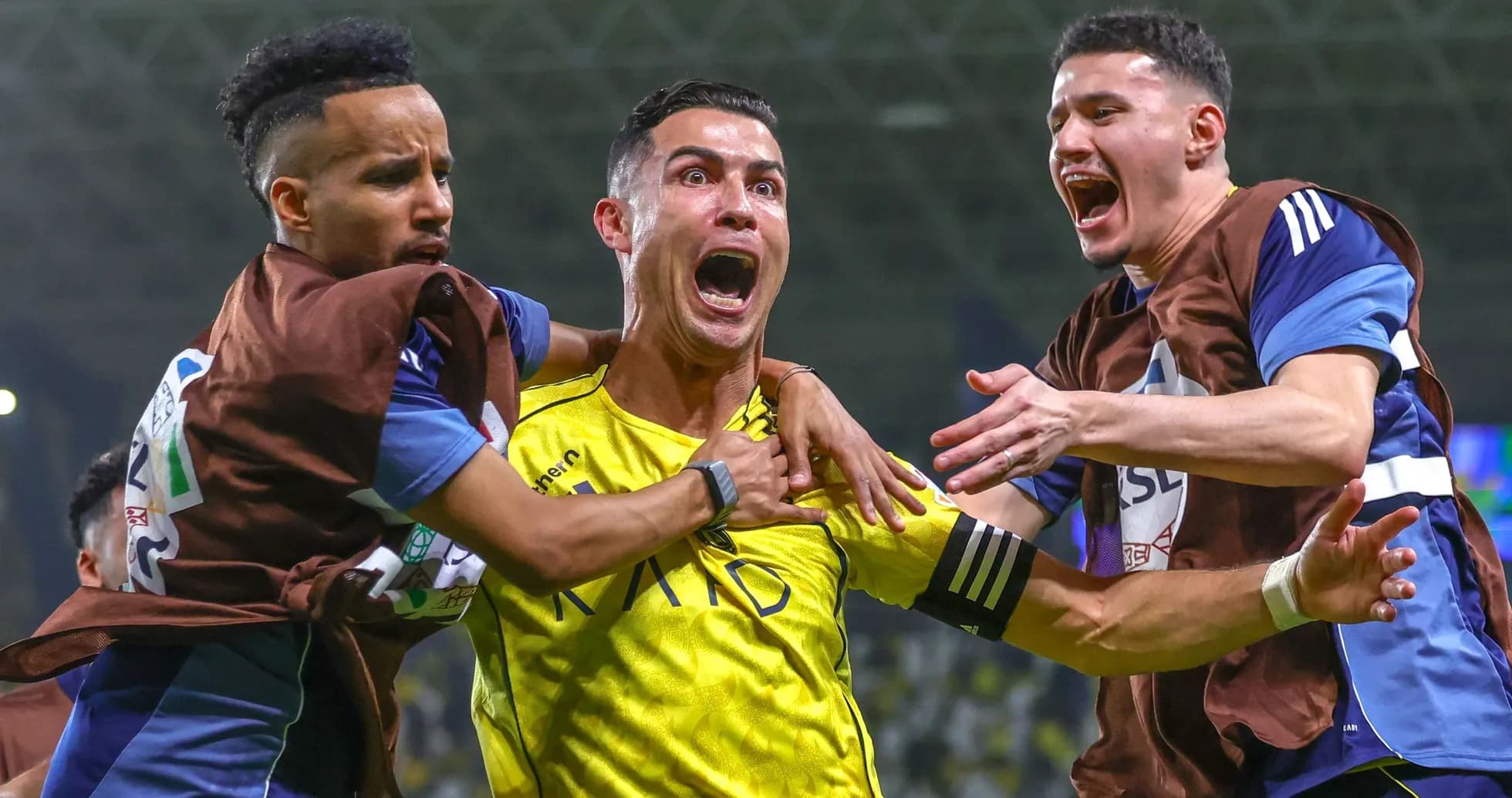 Three players celebrating a goal on the field