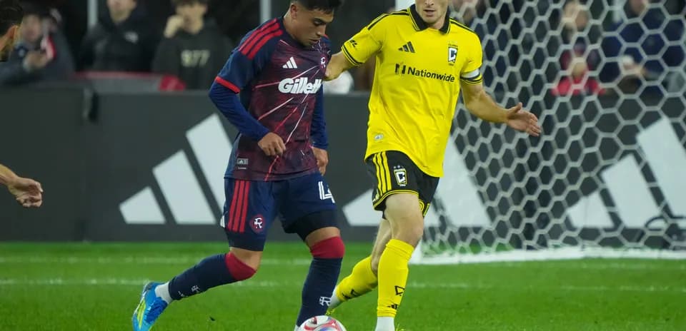 Columbus Crew player challenging New England Revolution player