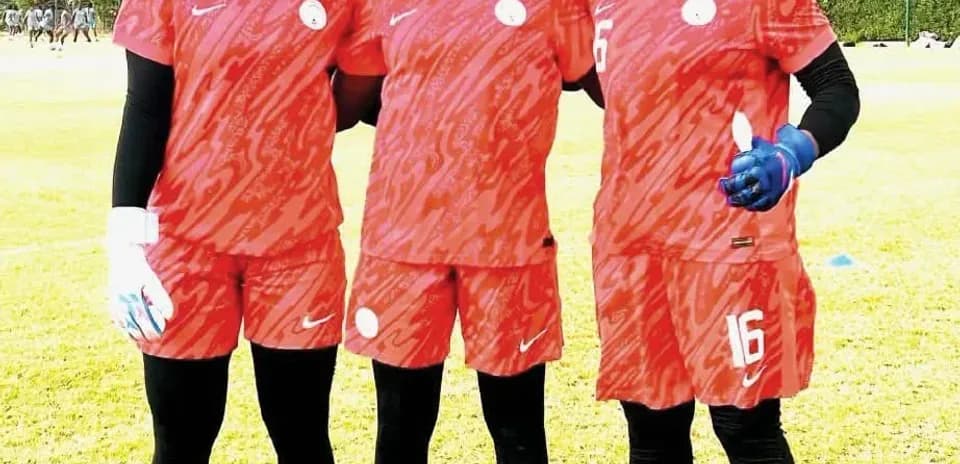 Three soccer players posing in training kits