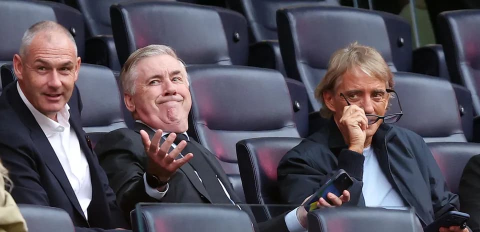 Three men seated in a stadium watching a game